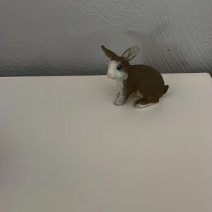 Schleich kanin - Charmig liten kaninfigur i brunt och vitt. Perfekt som dekoration i hemmet eller som en söt present. Figuren har fina detaljer och en naturlig pose.
