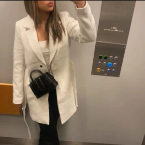 Vit kappa - Snygg vit kappa med klassisk design och långa ärmar. Perfekt för att ge en stilren look. Passar bra till både vardag och mer uppklädda tillfällen.