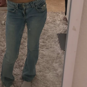 Ljusblå bootcut jeans - Snygga ljusblå bootcut jeans med låg midja. Perfekta för en avslappnad stil. Klassisk femficksdesign och dragkedja med knapp framtill. Strl men går att spänna in och ut.