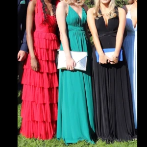 Grön klänning från Ivory Field - Skogsgrön klänning som är perfekt för bal/student/gask! 🩷Använd 1 gång på bal och tvättad hemma så ser iprincip ny ut. Storlek 4=S. Är sydd några få stygn  där fram, går att sprätta upp. Kan knytas på olika sätt vid ryggen/justera längden på klänningen med snörena. Jag var ca 180cm med klackar och den nådde precis till golvet. Har ett slit. Nypris 1.899kr. Skicka meddelande om du även är intresserad av kuvertväskan, den är guldig, så kan vi diskutera ett passande pris!