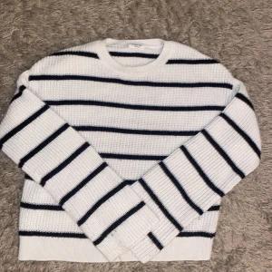 Vit och svart randig tröja från Kappahl - Säljer en stilren vit tröja med svarta ränder från Kappahl. Tröjan är stickad och har långa ärmar, perfekt för en avslappnad look. Den är i storlek 158/164 och passar bra till både jeans och kjol.