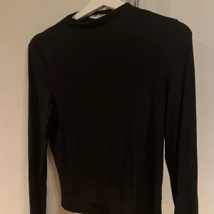 Svart långärmad tröja från NA-KD - Säljer en stilren svart långärmad tröja från NA-KD. Perfekt för en minimalistisk look och passar till många olika outfits. Tröjan är i storlek M och har väldigt mjukt tyg.