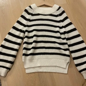 Randig stickad tröja - Säljer en mysig stickad tröja med svartvita ränder. Tröjan har långa ärmar och en rund halsringning. Perfekt för kyligare dagar. Ifrån Lindex i storlek 128! Men jag är 14 år och den passar fortfarande! 