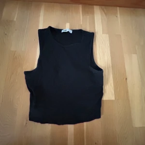 Svart ärmlös topp från Zara - Säljer en stilren svart ärmlös topp från Zara. Perfekt för lager-på-lager eller att bära som den är. Toppen har en enkel design och är gjord i ett mjukt material.