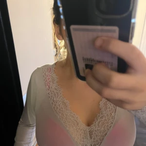 Grå långärmad topp med spetsdetaljer - Säljer en elegant grå långärmad topp med vackra spetsdetaljer vid halsringningen.