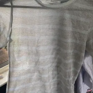 T-shirt i glittrig mesh med ljusblåa och silvriga ränder.  Stretchig i materialet, passar på s/xs men även på M om man vill ha en tight fit. Bra skick