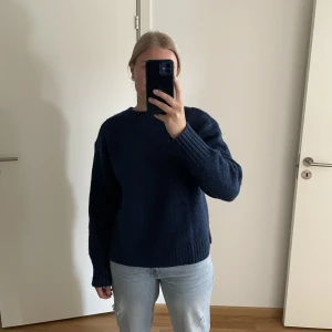 Blå stickad-tröja - En mörkblå stickad tröja från HM i storlek M! Den är knappt använd och har en slits på båda sidor längst ner vilket gör att den faller väldigt fint💙Se sista bilden för bättre ljus, där syns färgen på tröjan bättre☺️