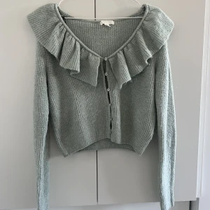 Ljusgrön stickad tröja  - En ljusgrön stickad tröja med volang som tyvärr inte kommer till användning längre 