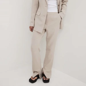 Beiga kostymbyxor med slits  - Säljer dessa fina kostymbyxor i storlek 36, säljer dessa för att storleken är för stor.De har prislappen kvar och aldrig använda.