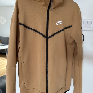 NY Nike tech fleece Stl S - Nike tech fleece Stl S, beige-brun. Aldrig använd, bara testad hemma. En julklapp till sonen som aldrig har använts. Inhandlad på The Athlete’s Foot i december, kvitto finns. 