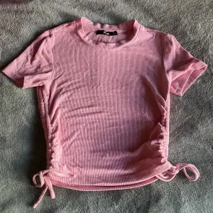 En rosa T-shirt som har knyten på sidan. Passar med mycket och har väldigt stretchigt och mjukt👍