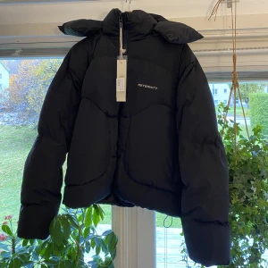 Pufferjacka - Jag säljer denna svarta pufferjacka med avtagbar luva ifrån märket ”Reternity”. Nypris låg på 2880 kr, nu är den helt slutsåld på deras hemsida.  Den är i storlek M men i en oversized modell, så den motsvarar snarare en storlek L. Aldrig använd. 