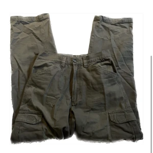 Olivgröna cargobyxor - Cargobyxor som är köpta second hand! De har inga tecken på användning och har riktiga fickor! använd gärna köp nu <3 Midja: ca 36 cm Innerbenslängd: 78 cm