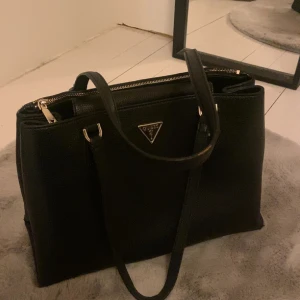 Guess väska  - Säljer min jätte fina guess väska💕 Den är i bra skick men en liten del av dragkedje grejen på baksidan saknas men annars funkar allt som de ska 💕