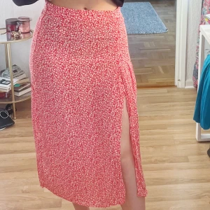 Blommig kjol - Röd kjol med vita blommor och slits🌸🌸🌸 bara använd 1 gång på konfirmation så den är i nyskick!