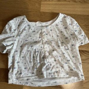 Blommig topp - Blommig topp med knappar. Sparsamt använd. 