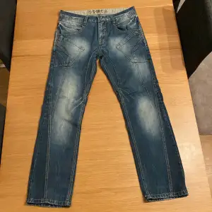 Ett mörkblått par jeans med extremt snygg wash och detaljer. Extra fickor vid låren, snygga distressed bakfickor och längs hela året finns tydliga sömmar. Ganska långa! W34/L34 (Men känns lite mindre om jag ska vara ärlig) Skriv om det finns frågor :)