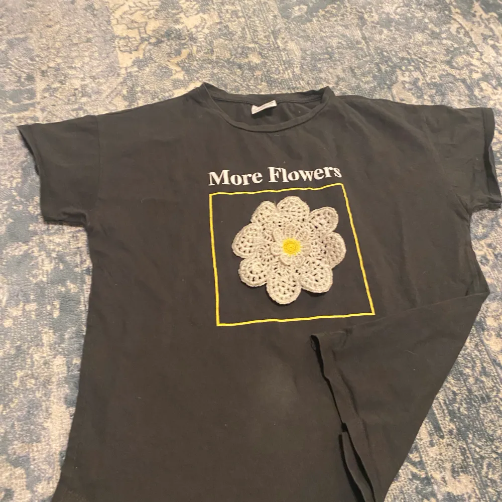 En tröja med en stor blomma i mitten. T-shirts.