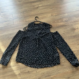  Topp - Topp från Gina tricot i svart/vit prickig mönster och som använd några gånger. Öppen vid axlarna. Passar med vita/svarta byxor och jeans byxor. Normal i storlek, är i mycket bra skick.