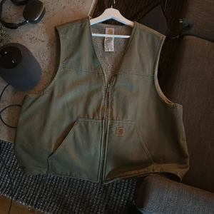 Carhart väst, grön XXL - Grön carhartväst i 2xl. Köpt 2021 begagnad och är i mycket bra skick. Möts gärna i Stockholm men kan skicka vid behov!