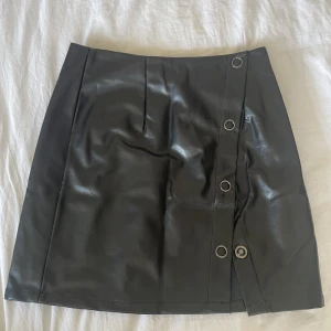 Kjol i pu - Säljer denna helt nya pu-kjol. Knäppning för att välja om man vill ha högre slits. 