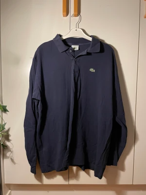Långärmad piké - Långärmad marinblå lacoste piké köpt second hand på humana. Stor i storleken. Köparen står för frakten! Priset går att diskutera.