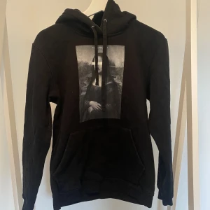 svart Hoodie - Svart Hoodie med Mona Lisa tryck i storlek S ifrån the cool elephant.