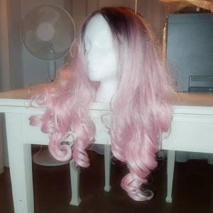 Rosa ombre peruk  - Sällan använd. Mest legat i en låda. Är något tilltufsad och tovig på sina ställen pga det men i övrigt fin.   (Obs se bild och avgör själv).   Går säkert att kamma ut om det skulle viljas 
