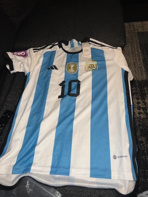 MESSI Argentina world cup Jersey 2022 - Den hära tröjan e helt o fräsch ny pakat aldrig testat ba att den e small för mig. Helt ren och allt kommer med namn nummer och patch. Säljs för samma pris som köptes 