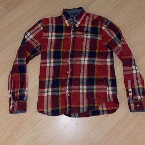 ”New zealand” Röd rutad skjorta - En fin ”New zealand” röd rutad skjorta, väldigt stabil kvalité. Detta är en tjockare skjorta och materialet är väldigt bekvämt.