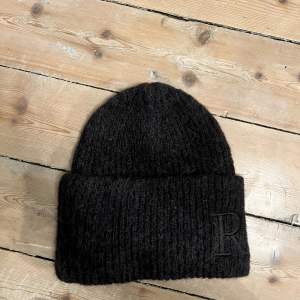 Rodebjer Sendina Oversized beanie Använd en gång. Säljer pga. passar inte riktigt mitt huvud. Det är svårt att fånga färgen på bild, den är gråsvart.  Lappen inuti mössa märkt Rodebjer har lossnat, men kan enkelt sys dit om man vill ha kvar den. 