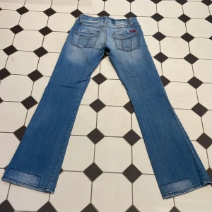 Lågmidjade jeans - Lowwaist jeans med lätt utsvängda ben. Midjemått tvärs över 36cm innerbenslängd 77cm. Obs har en fläck se sista bilden