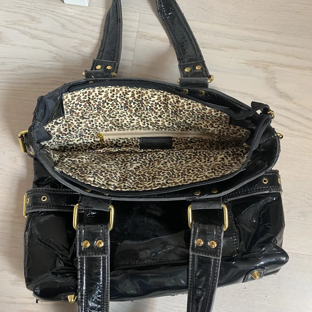Super fin lack väska med leopard print, som rymmer massor! Lacket håller däremot på att lossna på både axelbanden och ”sidorna” och därför blir det som små svarta korn efter väskan. Det finns ett annat axelband i väskan om man vill ha det istället <3 . Väskor.