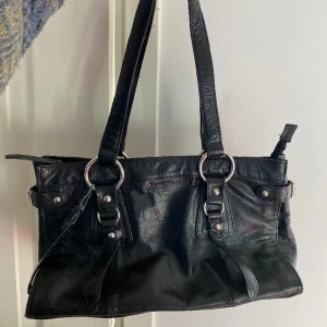 Väska - Svart vintage skinnväska med fina detaljer. Fransat sig något på bandet. Märket är Maharani of Tirapunji. 