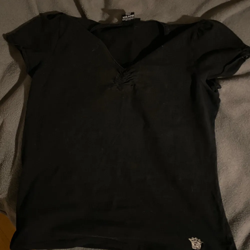 En vanlig söt svart T-shirt med en liten silverkrona i vänstra hörnet.  Använd typ 2 gånger . T-shirts.