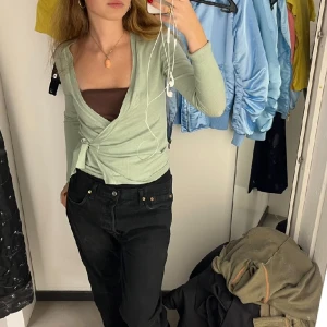 Grön Filippa K tröja som knyts  - Jättesöt mint grön tröja som knyts där fram som ett ballerina linne. Tröjan är ganska elastiskt och i bomull, andvänd sellan så fint skick. Sitter som en xs-s men skulle också passa m. 