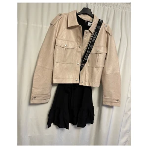 Set från Na-kd, Nytt! Jacka & klänning  - Storlek 34  Svart ljuvlig klänning.  Samt kortare biker jacka i ormskinns imitation.  Helt nytt!  Allt säljes i ett set!  Väska & halsband ingår ej! 