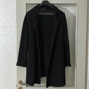 Svart kofta  - Svart kofta med smalt skärp i midjan. Koftan är köpt i hm och är storleken M. 