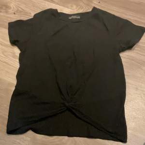 Ribbad svart T shirt ,ed en ”snurr” fram