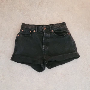 Svarta jeansshorts - Svarta jeansshorts från Lager 157 i storlek M. Har fickor både fram och bak. 4 knappar i fram som stänger shortsen, men enbart en som syns, se bild! Säljer p.g.a. att de är lite för stora för mig. 