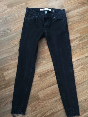 Jeans - Svartgråa jeans med slitning/klippning nertill