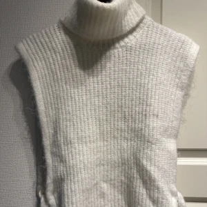 Stickad väst - Vit stickad väst med knyte i sidorna. 