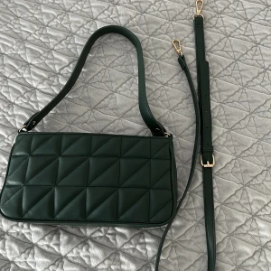 Mörk grön crossbody och Axel väska  - Den kan man ha både som crossbody väska men även Axel väska. Den har en ficka på insidan. 