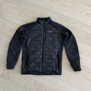 Svart peak performance jacka  - Svart hybrid jacka från peak performance. Strl L, normal i storleken, aldrig använd. En dam modell men passar bra till både dam och herr.  Inköpspris ny 2 400kr
