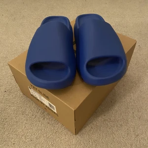 Yeezy slides ”azure” - Tjena! Jag säljer yeezy slides ”azure” som är helt oanvända i skick 10/10🤩. Kvitto finns✅, det är bara att meddela! Om du har några frågor eller om du vill ha fler foton på skorna är det bara att meddela! 📸😃