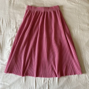 Rosa midikjol - Plisserad kjol från bikbok. Storlek XS men den är väldigt stretchig i midjan så passar även S bekvämt! I fint skick, kan gärna skicka fler bilder då materialet var lite svårfångat på bild.