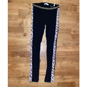 Leggings H&M - Svarta Leggings med leopard rand på sidan av benen och 2 guld ränder i resoren i midjan. Använd få gånger i storlek 164 