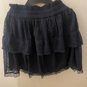 Kjol - En snygg mörkblå kjol med volanger!💙 Den är kort och har blommigt mönster på sig! Den är stretchig så skulle säga att den passar S-M. Hör av er vid funderingar 🌸