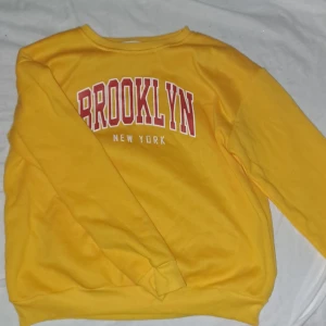 Tröja - En mörk gul tröja med text 