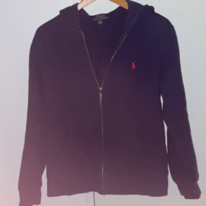 Ralph Lauren Zip Hoodie - Säljer min marinblåa/mörkblåa zip hoodie från Ralph lauren i storlek 14-16. Hoodien är i bra skick och har inga defekter. Hör gärna av er vid frågor eller om ni vill ha fler bilder.